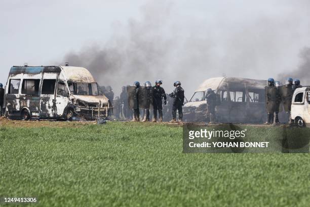 French gendarmes stand next to burnt gendarmes' cars on the sideline of a demonstration called by the collective "Bassines non merci", the...