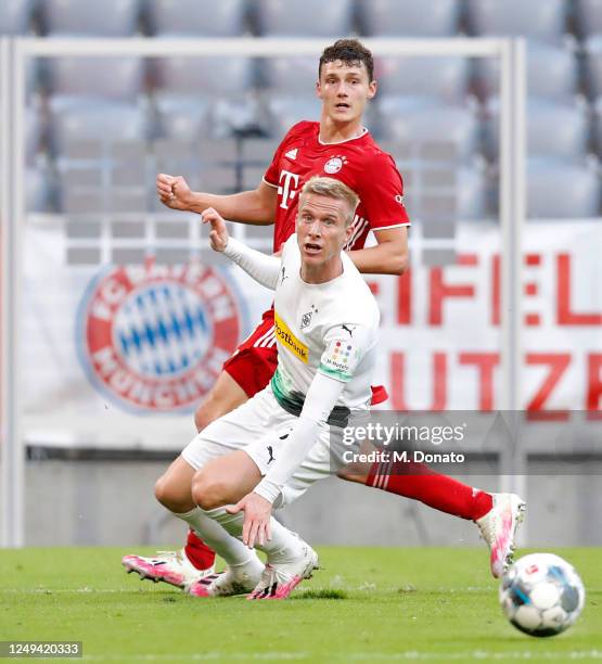 Benjamin Pavard of Muenchen passes the ball past Oscar Wendt of Moenchengladbach to assist teammate Leon Goretzka scoring his team's second goal...