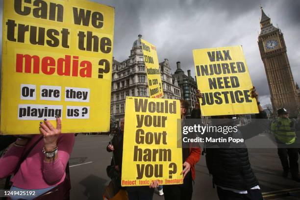 Protesters hold up signs criticising the covid vaccine in Parliament Square on March 25, 2023 in London, United Kingdom. Protesters gather to mark...