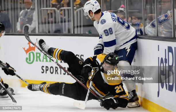Garnet Hathaway of the Boston Bruins is tripped by Mikhail Sergachev of the Tampa Bay Lightning during the third period at the TD Garden on March 25,...