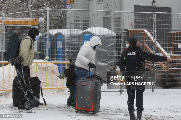 Royal Canadian Mounted Police officers greet refugees as they arrive at the Roxham Road border crossing in Champlain, New York, on March 25, 2023. -...