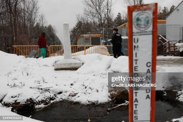 Royal Canadian Mounted Police officers greet refugees as they arrive at the Roxham Road border crossing in Champlain, New York, on March 25, 2023. -...