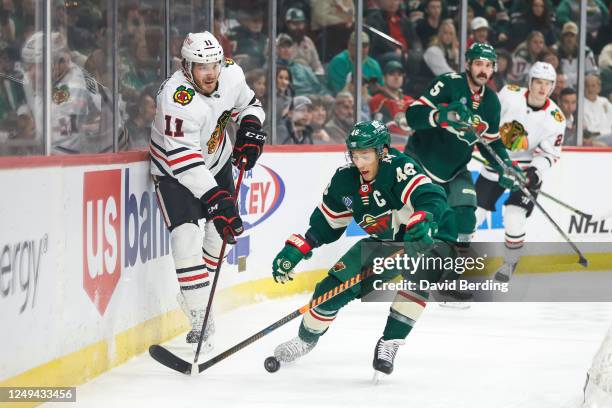 Taylor Raddysh of the Chicago Blackhawks and Jared Spurgeon of the Minnesota Wild compete for the puck in the first period of the game at Xcel Energy...