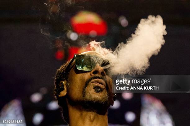 Rapper Calvin Cordozar Broadus Jr aka Snoop Dogg blows smoke as he performs on stage at the Accor Arena of Bercy, in Paris, on March 25, 2023.
