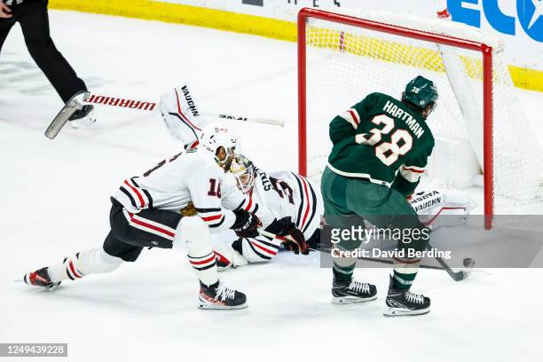 Ryan Hartman of the Minnesota Wild scores a goal against Alex Stalock of the Chicago Blackhawks while teammate Taylor Raddysh defends in the third...