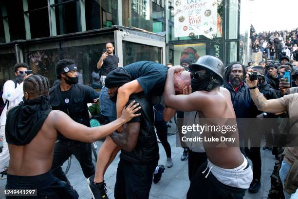 Group of men including Patrick Hutchinson help an injured man away after he was allegedly attacked by some of the crowd of protesters on the...