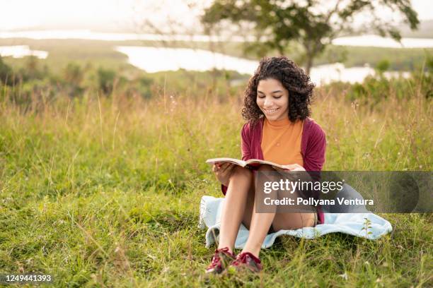 teenager reading a book and enjoying the sunset - children's literature stock pictures, royalty-free photos & images