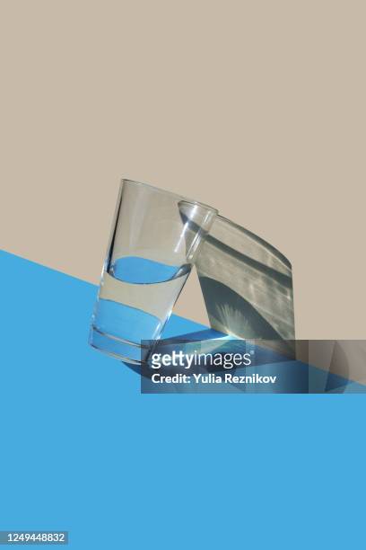 water in glas on the blue-beige background - wasserglas stock-fotos und bilder