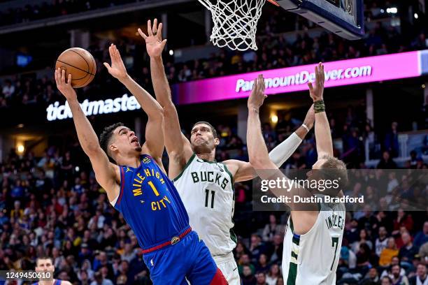 Michael Porter Jr. #1 of the Denver Nuggets scores under defense by Brook Lopez of the Milwaukee Bucks in the first half of a game at Ball Arena on...