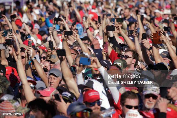 Supporters of former US President Donald Trump take photos as he arrives to speak at a 2024 election campaign rally in Waco, Texas, March 25, 2023. -...
