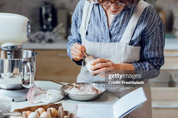 stap voor stap cookie bakken: een vrouw na een recept uit haar notebook - baking reading recipe stockfoto's en -beelden