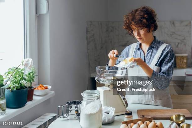 göra cookies hemma: en kvinna som väger smör - köksvåg bildbanksfoton och bilder