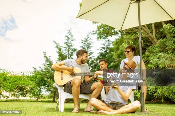 group of friends having fun, playing guitar and drinking yerba mate in the backyard - mate argentina stock pictures, royalty-free photos & images