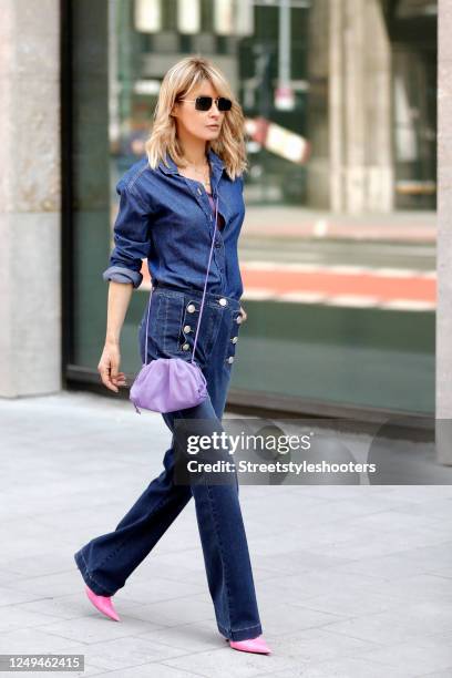 Influencer Gitta Banko, wearing a dark blue denim jeans shirt with 'what ever' lettering on the back by Lookabe, dark blue flared leg denim jeans by...