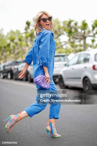 Influencer Gitta Banko, wearing a blue denim jeans overall by One Teaspoon, a purple mini pouch bag by Bottega Veneta, multi colored sandals by...