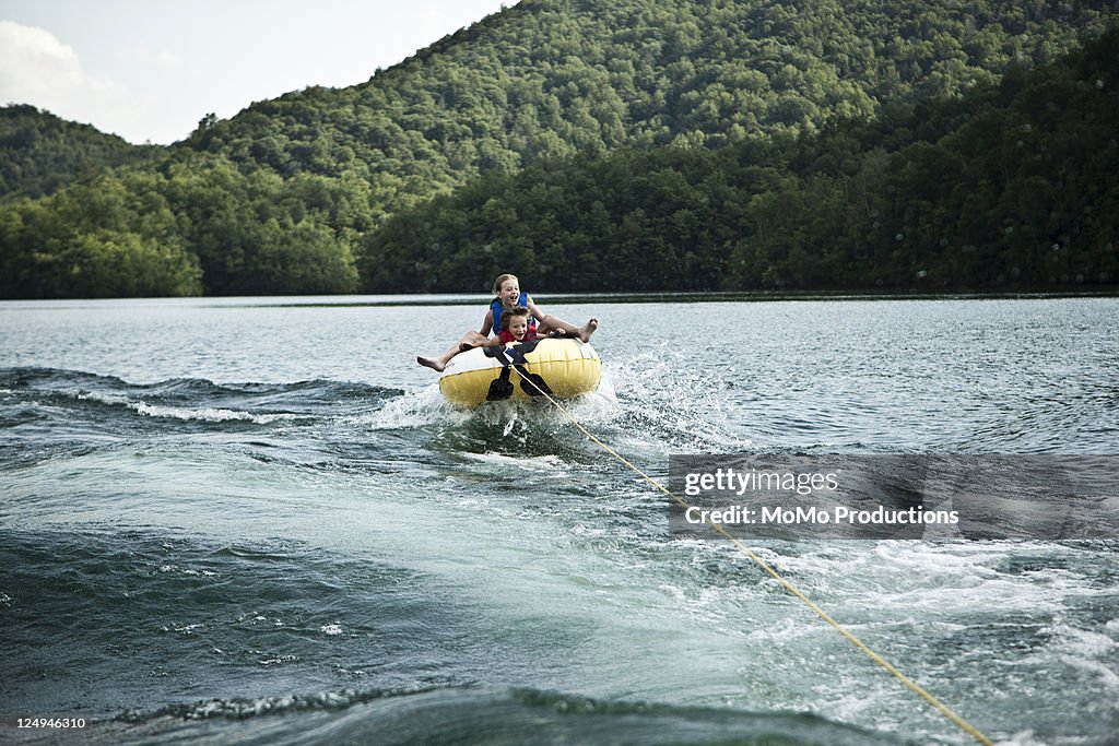 Kids on tube behind boat.