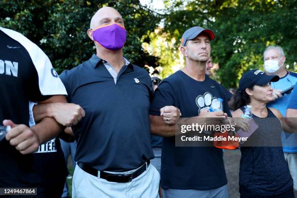 From left, Clemson University president James P. Clements, football coach Dabo Swinney, and Kathleen Swinney lock arms in prayer during the "March...