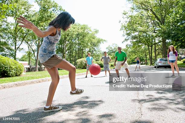 kids playing kickball in a suburban neighborhood - girl kicking stock pictures, royalty-free photos & images