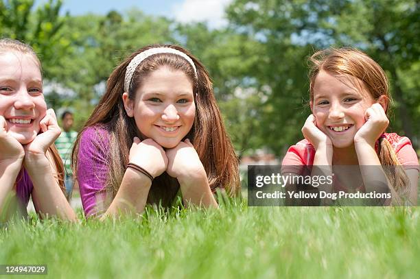 portrait  of smiling girls lying in the grass - happy tween girls lying on grass stock pictures, royalty-free photos & images