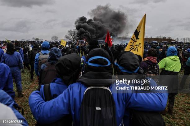 Protesters watch a gendarmes' vehcile burning during a demonstration called by the collective "Bassines non merci", the environmental movement "Les...