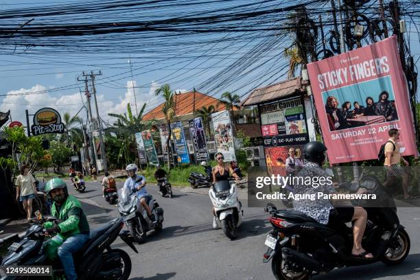 Foreigner tourist rides a motorcycle without helmet at a main road on March 26, 2023 in Canggu, Bali, Indonesia. Indonesian island of the gods plans...