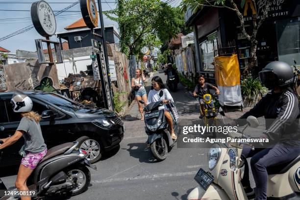 Foreigner tourist rides a motorcycle without helmet at a main road on March 26, 2023 in Canggu, Bali, Indonesia. Indonesian island of the gods plans...