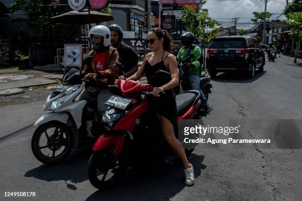 Foreigner tourist rides a motorcycle without helmet at a main road on March 26, 2023 in Canggu, Bali, Indonesia. Indonesian island of the gods plans...