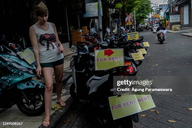 Foreigner tourist is looking for a rental motorcycle at a main road on March 26, 2023 in Seminyak, Bali, Indonesia. Indonesian island of the gods...