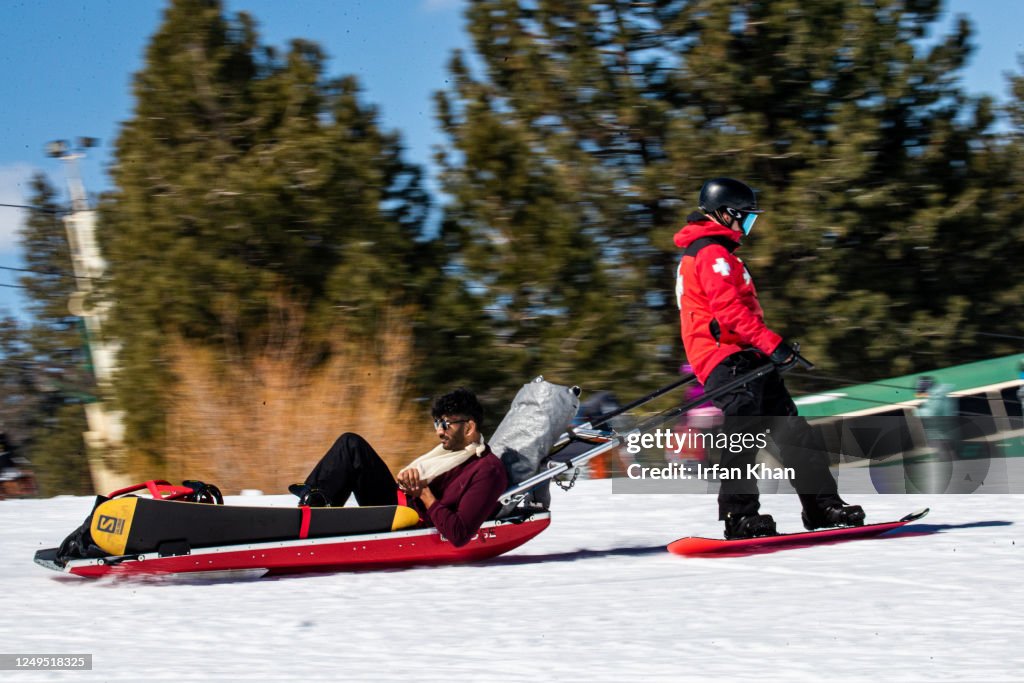 Slopson A paramedic brings an injured snowboarder down the slops on a sunny ...