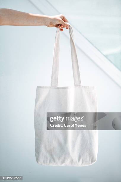 female hand holding a organig tote bag mock up - bolso tote fotografías e imágenes de stock