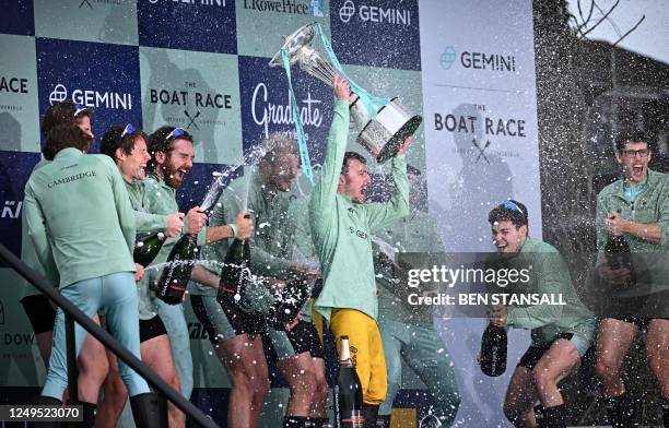 The Cambridge President Ollie Boyne is sprayed with champagne as he lifts the trophy after their victory in the 168th annual men's boat race between...