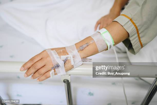 patient woman sleeping with receiving intravenous fluid directly into a vein while her hand touching bed rails on hospital bed. - iv drip womans hand stock-fotos und bilder