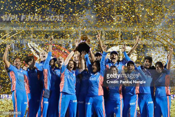 Players of Mumbai Indians pose with the Series Trophy after winning the Women's Premier League final match between Delhi Capitals and Mumbai Indians...