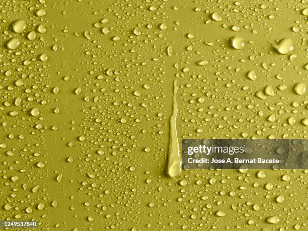 full frame of the textures formed by the bubbles and drops of water, slipping on the crystal of a window of yellow color. - condensation stock pictures, royalty-free photos & images