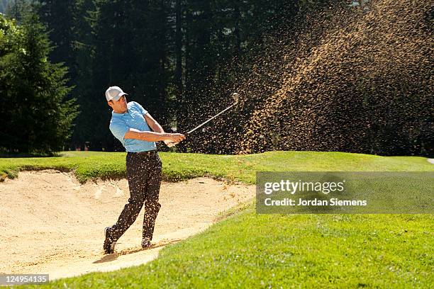 a man hitting out of a sand trap. - golf bunker fotografías e imágenes de stock