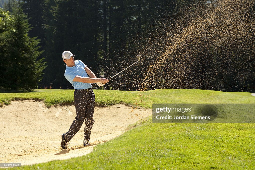 A man hitting out of a sand trap.