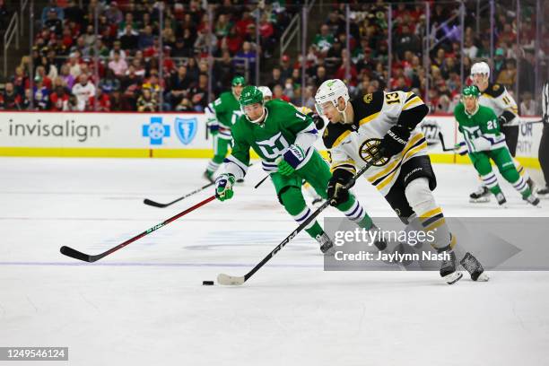 Charlie Coyle of the Boston Bruins skates with the puck guarded by Jack Drury of the Carolina Hurricanes during the second period of the game at PNC...