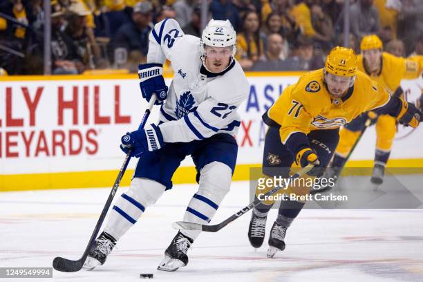 Rasmus Asplund of the Nashville Predators reaches in as Jake McCabe of the Toronto Maple Leafs skates past during the second period at Bridgestone...