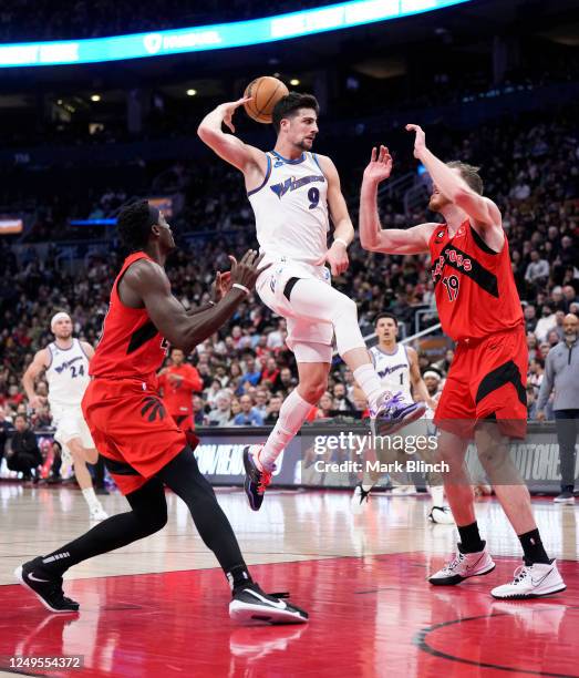 Deni Avdija of the Washington Wizards passes the ball off against Jakob Poeltl and Pascal Siakam of the Toronto Raptors during the second half of...