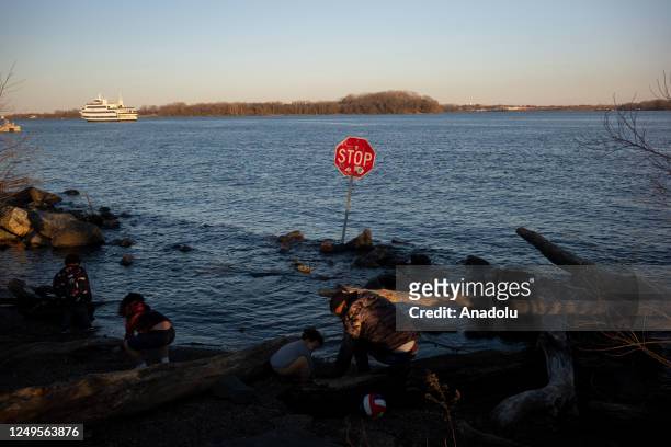 Children play along the Delaware River where a stop sign has been placed in the water at Penn Treaty Park in Philadelphia, Pa., on March 26, 2023....