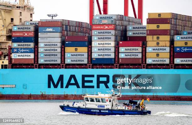 March 2023, Lower Saxony, Wilhelmshaven: A boat of the Lower Saxony water police sails along in front of the container ship "Morten Maersk" of the...