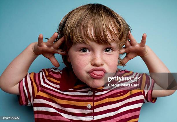 young boy making face - sticking out tongue stock-fotos und bilder