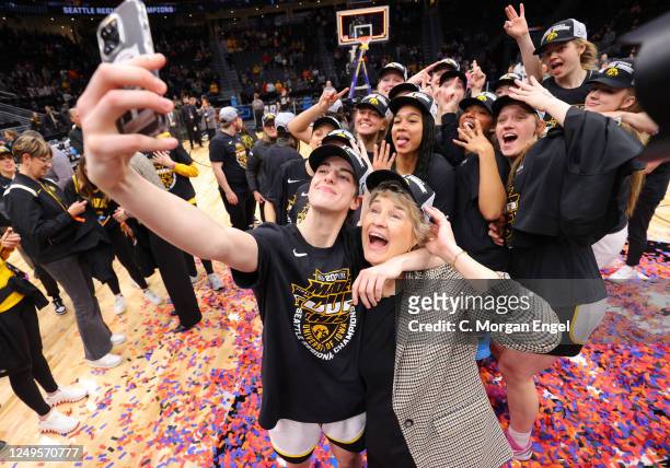 Caitlin Clark of the Iowa Hawkeyes takes a selfie with head coach Lisa Bluder after defeating the Louisville Cardinals during the Elite Eight round...