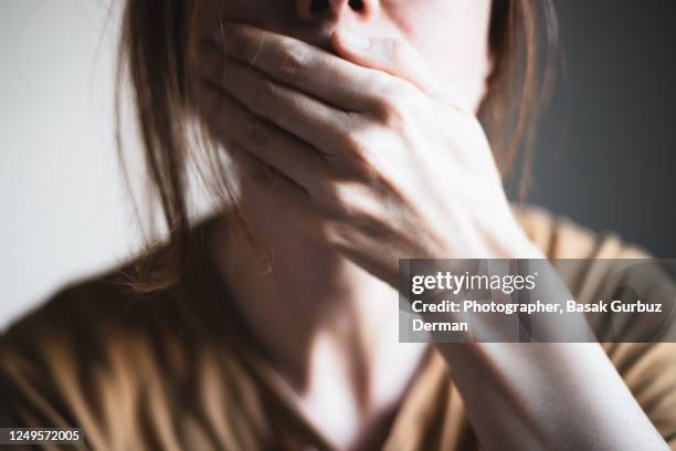 a woman covering her mouth with her hand - frau erschrocken stock-fotos und bilder