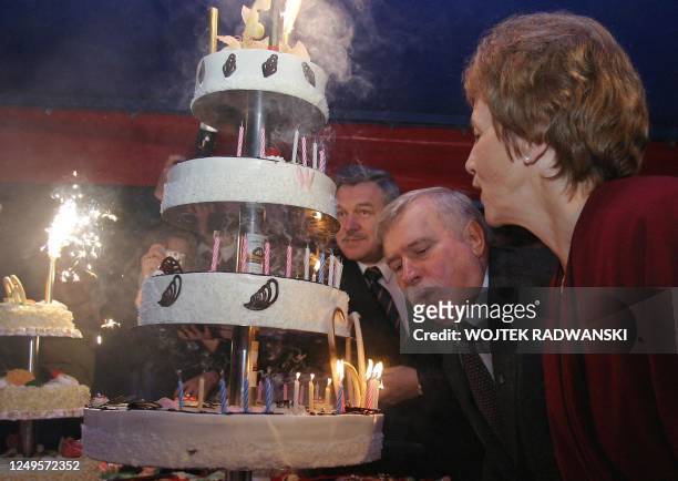 Polish former President Lech Walesa blows off candles on his birthday cake as his wife Danuta watches as he celebates his 60th birthday which was...