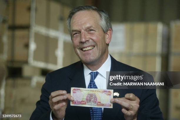 Commerce Secretary Donald Evans displays the new 25,000 Iraqi dinar bill during a ceremony at Baghdad international airport 15 October 2003 to mark...