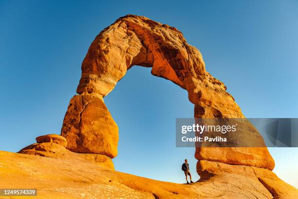 mann genießt zarten bogen in utah,usa - delicate arch stock-fotos und bilder