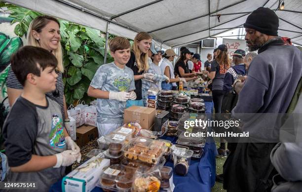 Volunteers, from left, James, Henry and Catherine, with their mom Christine Gay, hand out free food, including vegetables, meat, pastries, bread,...