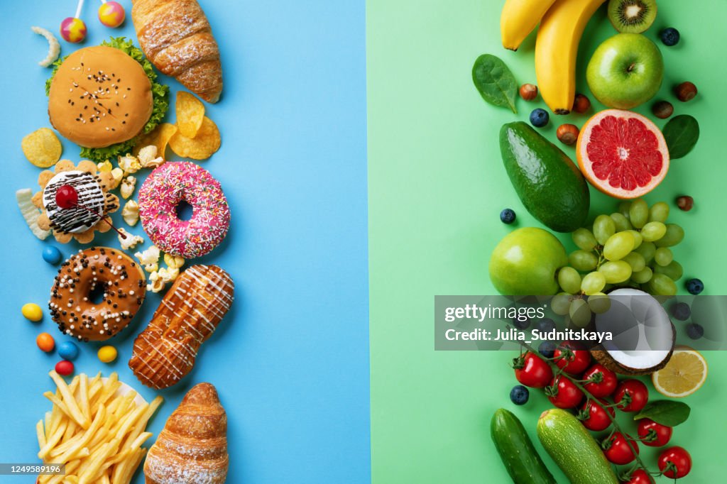 Healthy and unhealthy food background from fruits and vegetables vs fast food, sweets and pastry top view. Diet and detox against calorie and overweight lifestyle concept.