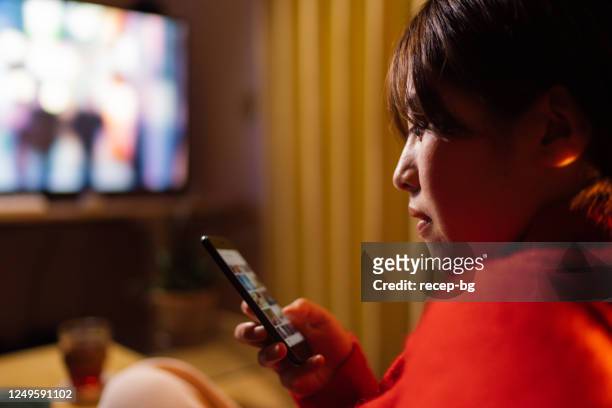 夜に家で映画を見ている若い女性 - 女性　部屋 ストックフォトと画像